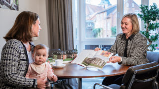 Sallier Immobilien Prokurist zeigt Frau im Prospekt Neubau Haus zum Kauf